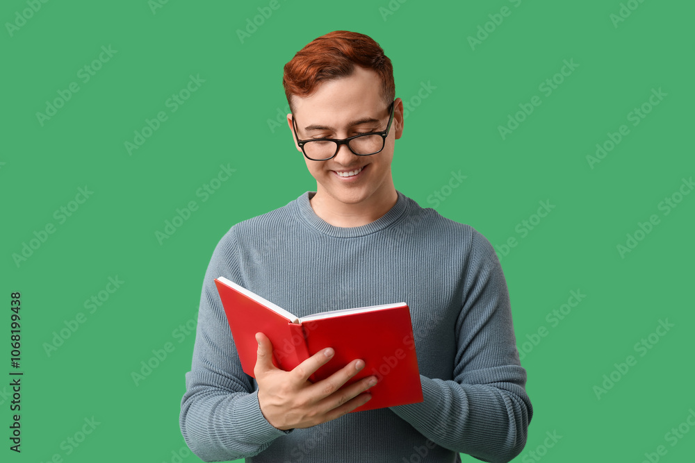 Young man in eyeglasses reading book on green background Young man in eyeglasses reading book on green background