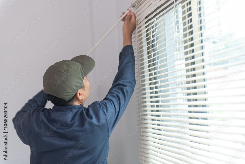 Uniformed repairman installs new window blinds in residential or commercial apartments. Blind installer. Professional service - Home repair and improvement. Uniformed repairman installs new window blinds in residential or commercial apartments. Blind installer. Professional service - Home repair and improvement.