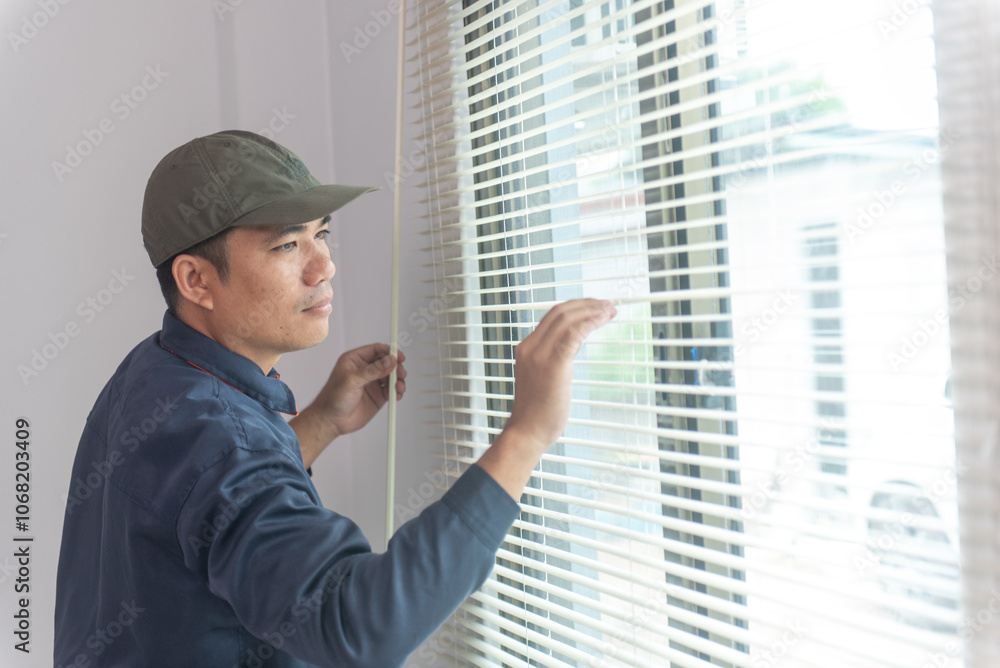 Fototapeta premium Uniformed repairman installs new window blinds in residential or commercial apartments. Blind installer. Professional service - Home repair and improvement.