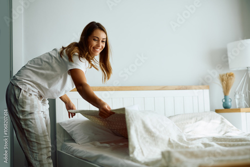 Obraz na plátně Happy woman making bed after waking up in  morning.