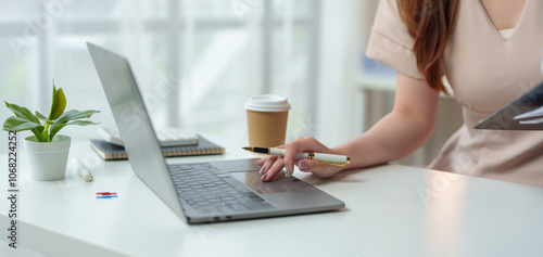 Confident Asian businesswoman working and checking work with laptop, holding files and smiling. Happy and successful Technology and relaxing coffee drinking at modern office.