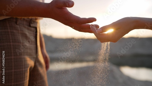 Фотография Couple pouring sand at sunset, symbolizing loss and time