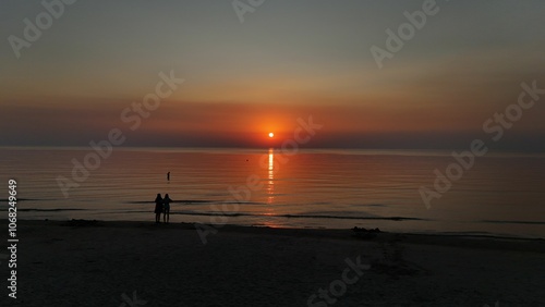 Serene beach sunset with silhouettes.