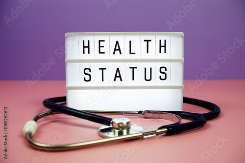 Health Status letterboard text on LED Lightbox and stethoscope on pink and purple background photo