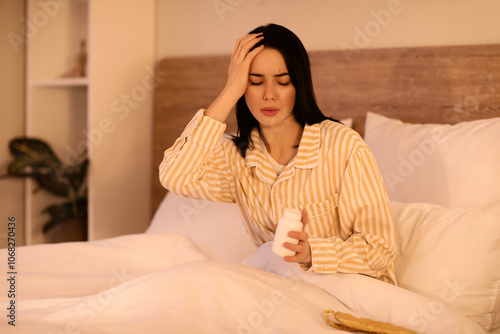 Pretty young woman with insomnia pills sitting in bed at night photo