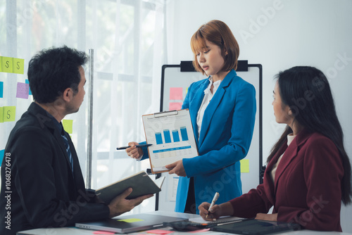 Business Presentation: A focused female executive confidently presents key data and insights to her attentive colleagues during a productive office meeting.