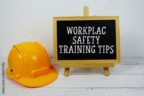 Workplace Safety Training Tips text on blackboard with safety helmet on wooden background photo