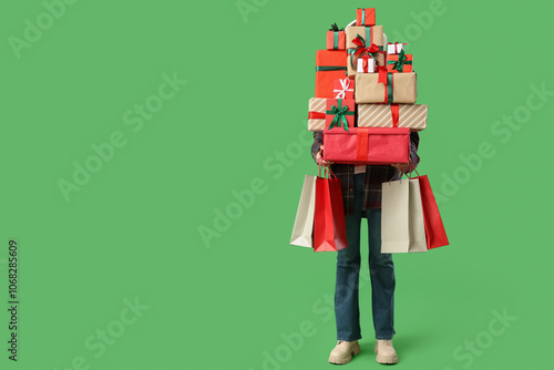 Beautiful young woman with shopping bags and gift boxes on green background. Christmas celebration