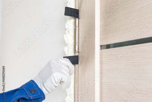 worker installs door gap expanders after mounting foam