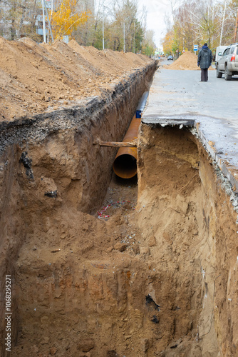 100 meters long large diameter water pipe in a earthen trench under the asphalt street surface. Repair, renovation of municipal equipment in the city photo