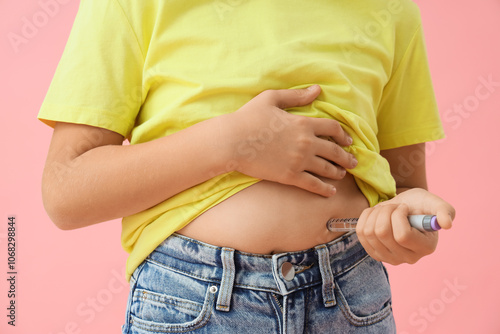 Diabetic girl using lancet pen on pink background, closeup