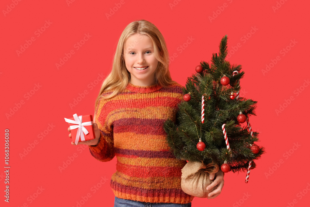 Cute girl with Christmas tree and gift box on red background Cute girl with Christmas tree and gift box on red background