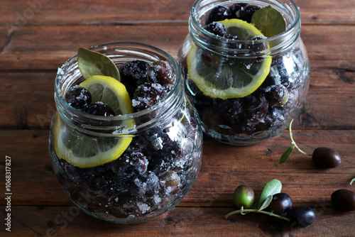 Olive nere fresche marinate in acqua, sale e limone in vasetti su fondo di legno. Direttamente sopra. photo