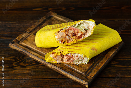 Shawarma, shawarma, doner with chicken, cheese and fresh vegetables on a wooden board on a wooden table. photo