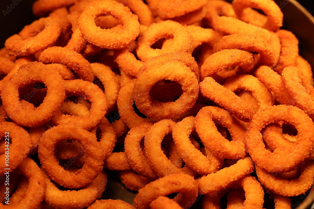 Vibrant orange rings of crunchy snacks piled high in a bowl, perfect for parties or casual munching. Vibrant orange rings of crunchy snacks piled high in a bowl, perfect for parties or casual munching.