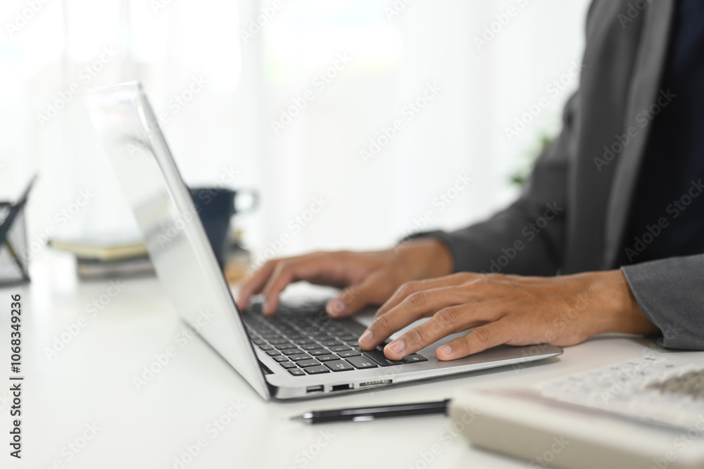 Close up of businessman typing on keyboard in modern workspace Close up of businessman typing on keyboard in modern workspace