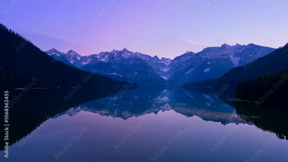 Evening with a calm atmosphere, a serene lake mirrors the sky and mountains in this wide video with a zoom out camera movement Evening with a calm atmosphere, a serene lake mirrors the sky and mountains in this wide video with a zoom out camera movement