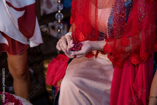 Close-up of a Bride's Hands at a Turkish Henna Night. Turkish Bride Holding Red Roses at Traditional Ceremony.