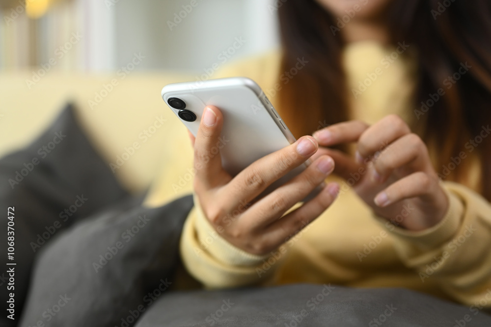 Young woman typing text message on mobile phone and relaxing on couch at home Young woman typing text message on mobile phone and relaxing on couch at home