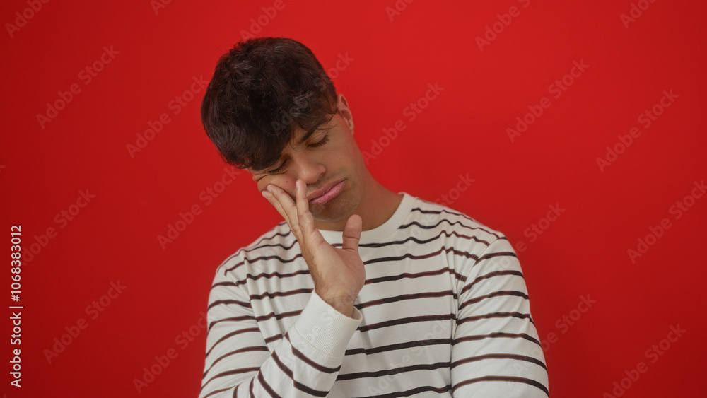 Handsome young hispanic man looking tired, isolated over a vibrant red background, portraying fatigue and weariness. Handsome young hispanic man looking tired, isolated over a vibrant red background, portraying fatigue and weariness.