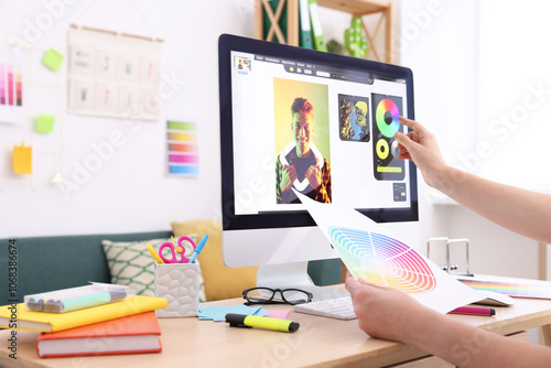 Designer with color palette working at wooden table indoors, closeup