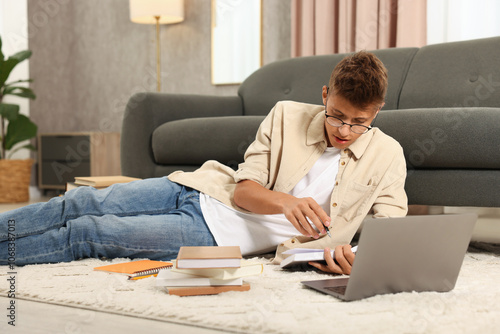 Student in glasses studying on floor at home