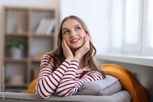 Charming young woman on sofa at home. Autumn atmosphere