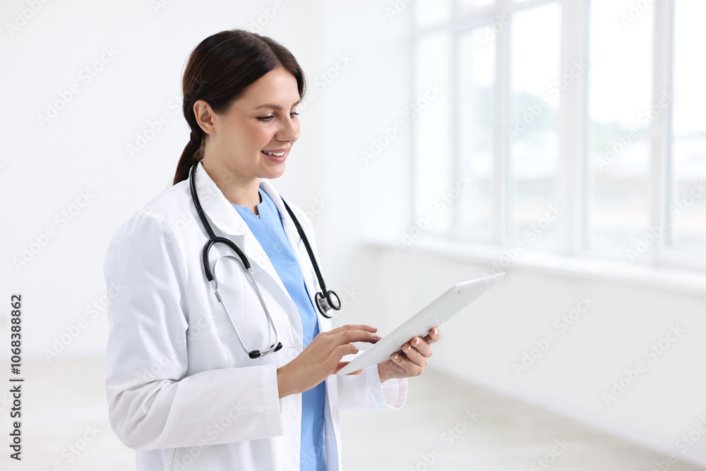 Smiling healthcare worker using tablet in hospital Smiling healthcare worker using tablet in hospital