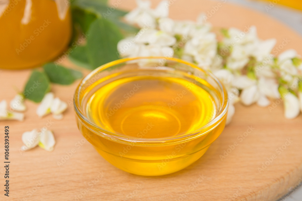 Sweet honey jar surrounded spring acacia blossoms. Honey flows from a spoon in a jar. jars of clear fresh acacia honey on wooden background Sweet honey jar surrounded spring acacia blossoms. Honey flows from a spoon in a jar. jars of clear fresh acacia honey on wooden background