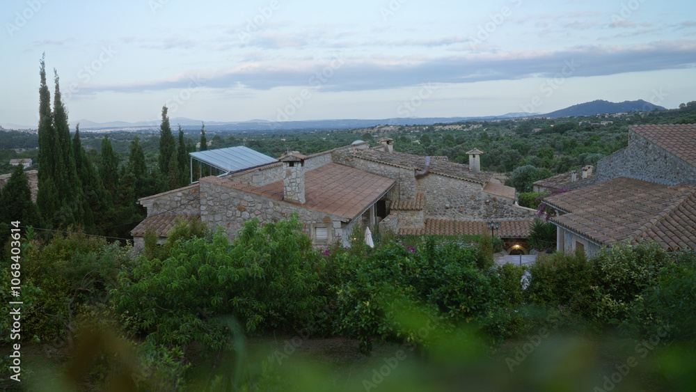 Rustic stone houses in the countryside of mallorca, spain, surrounded by lush greenery and overlooking a vast landscape of distant mountains. Rustic stone houses in the countryside of mallorca, spain, surrounded by lush greenery and overlooking a vast landscape of distant mountains.