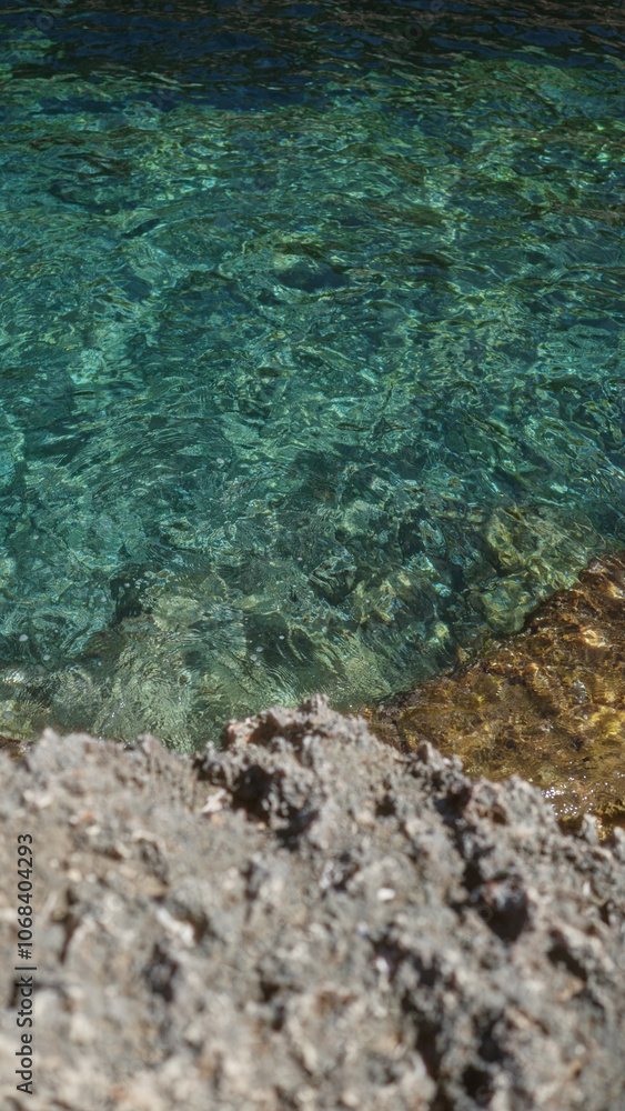 Fototapeta premium Clear water flowing over rocks in a serene outdoor setting in mallorca, spain, with vibrant colors reflecting off the surface.