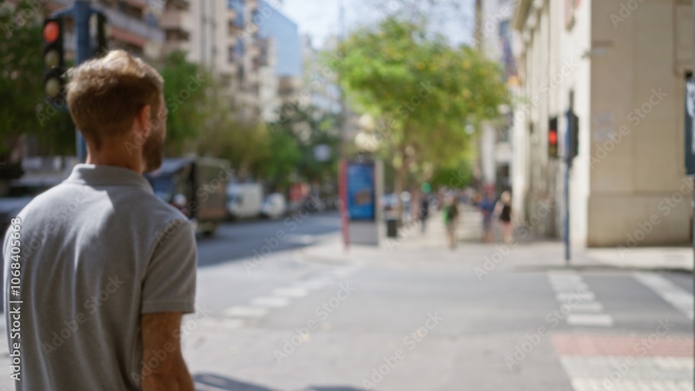 Man walking along a blurred city street with buildings and people defocused in the background on a sunny day Man walking along a blurred city street with buildings and people defocused in the background on a sunny day