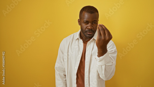 Young man making italian hand gesture against a vibrant yellow background, embodying style and charisma.