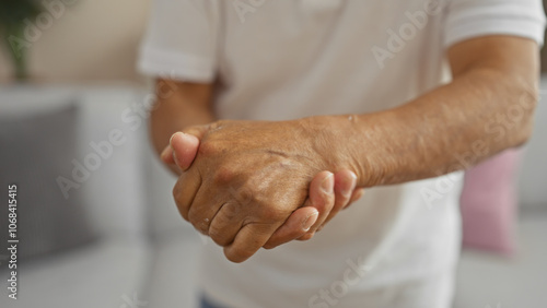 A middle-aged man holding his hands in a room suggests an indoor setting with mature focus amidst a calm home environment.