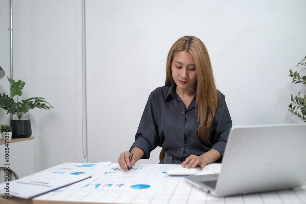 A woman is sitting at a desk with a laptop and a stack of papers A woman is sitting at a desk with a laptop and a stack of papers