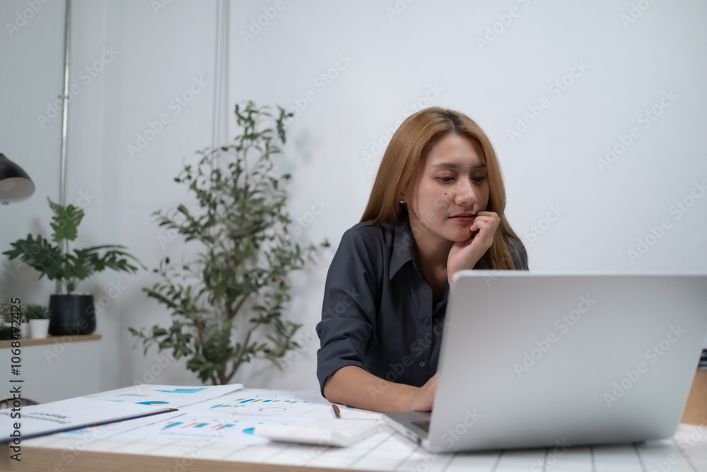 A woman is sitting at a desk with a laptop open in front of her A woman is sitting at a desk with a laptop open in front of her