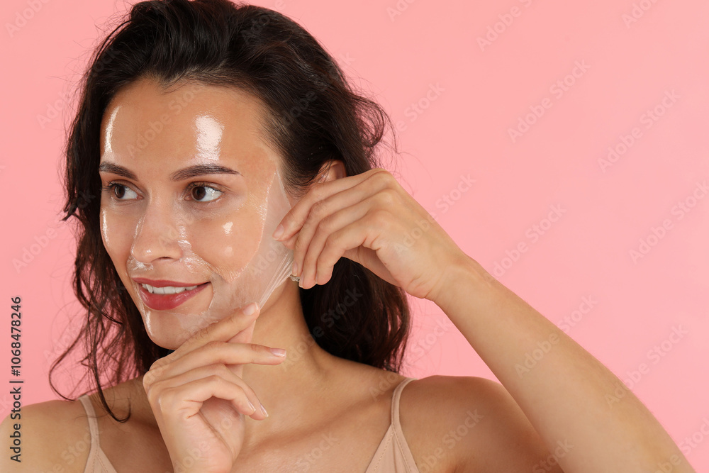 Smiling woman peeling off face mask on pink background Smiling woman peeling off face mask on pink background