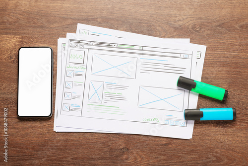 Developing UI design. Sketches of website wireframes, smartphone and felt pens on wooden table, top view photo