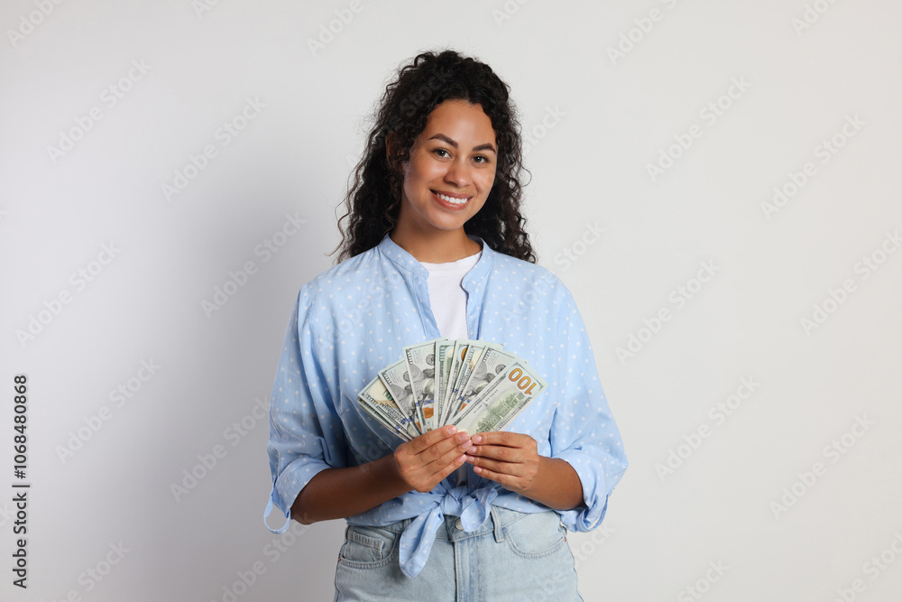 Happy woman with dollar banknotes on light grey background Happy woman with dollar banknotes on light grey background
