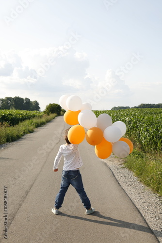 Girl standing on a street holding balloons