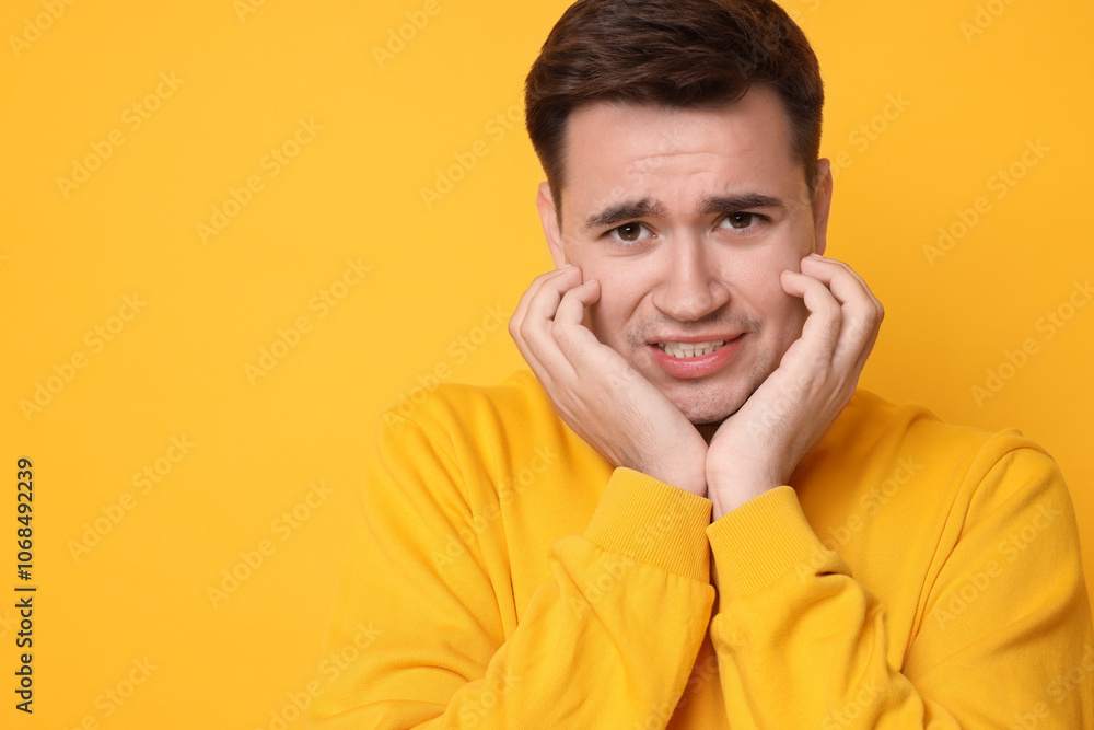 Portrait of scared young man on orange background, space for text Portrait of scared young man on orange background, space for text