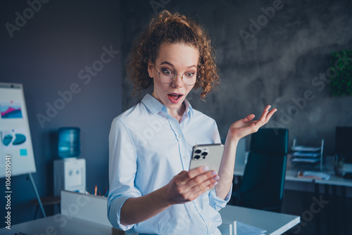 Young businesswoman in formalwear having a surprised reaction at her workstation in a modern office photo