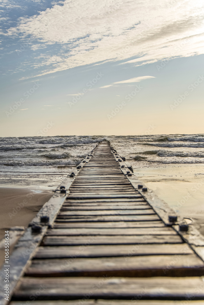Obraz premium Long pier boardwalk leading out onto a Baltic sea, sunrise long way out