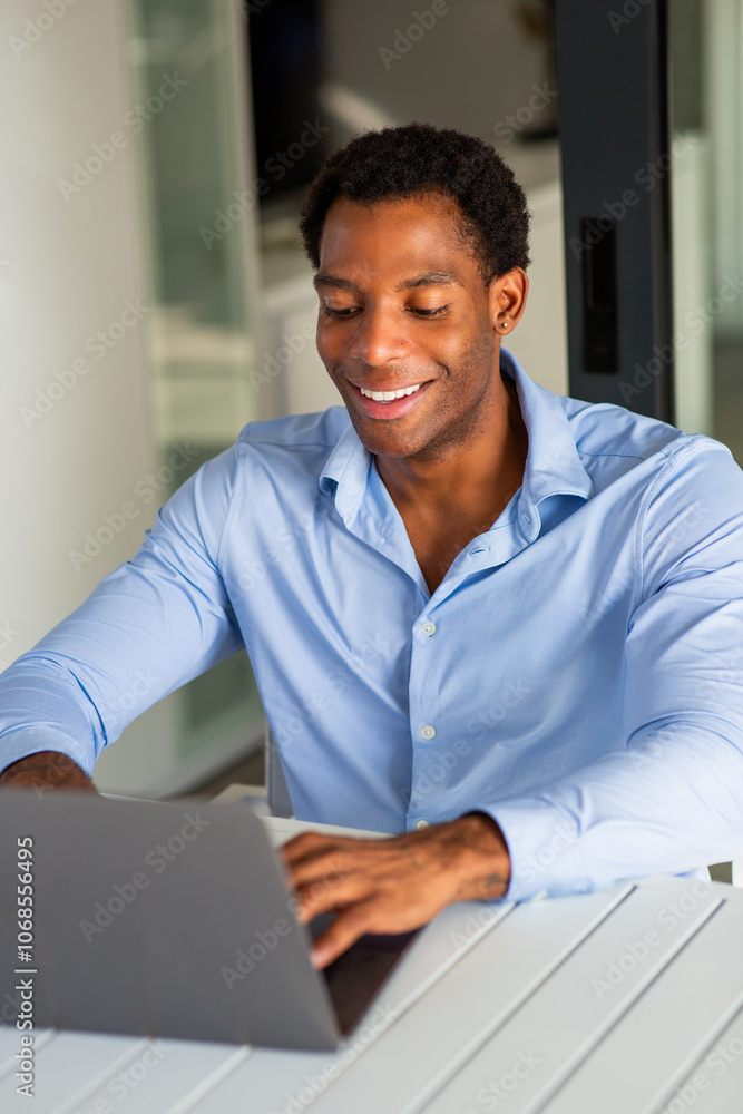 Man smiling while typing on laptop at table Man smiling while typing on laptop at table