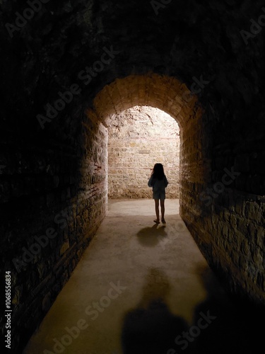 Young child walking along a tunnel, parents shadows in foreground