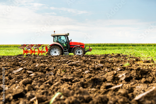 Agricultural tractor tilling fertile soil, readying the field for sowing photo