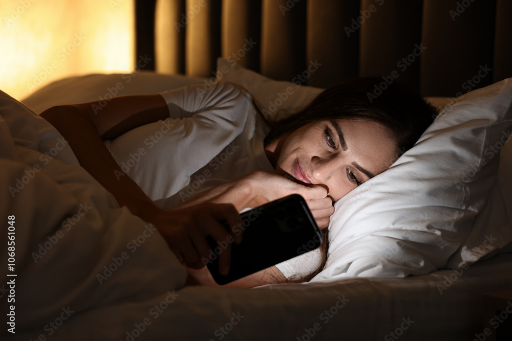 Bad habit. Young woman using smartphone in bed at night Bad habit. Young woman using smartphone in bed at night