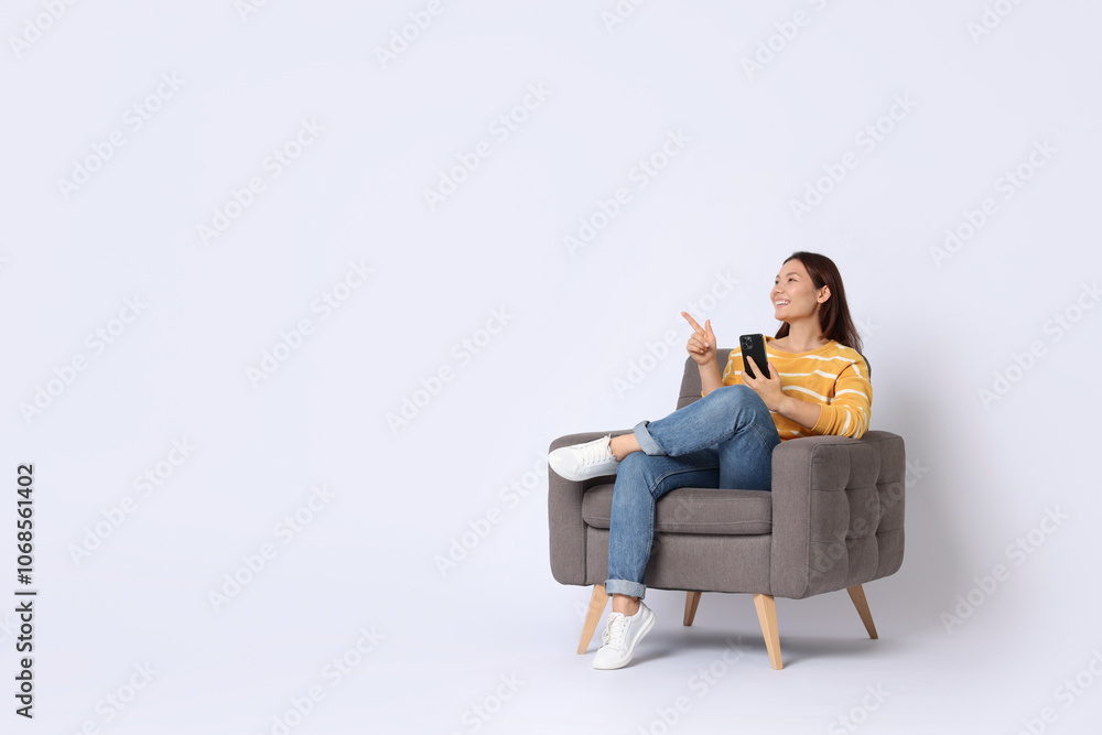 Smiling woman with smartphone sitting in armchair on white background. Space for text Smiling woman with smartphone sitting in armchair on white background. Space for text