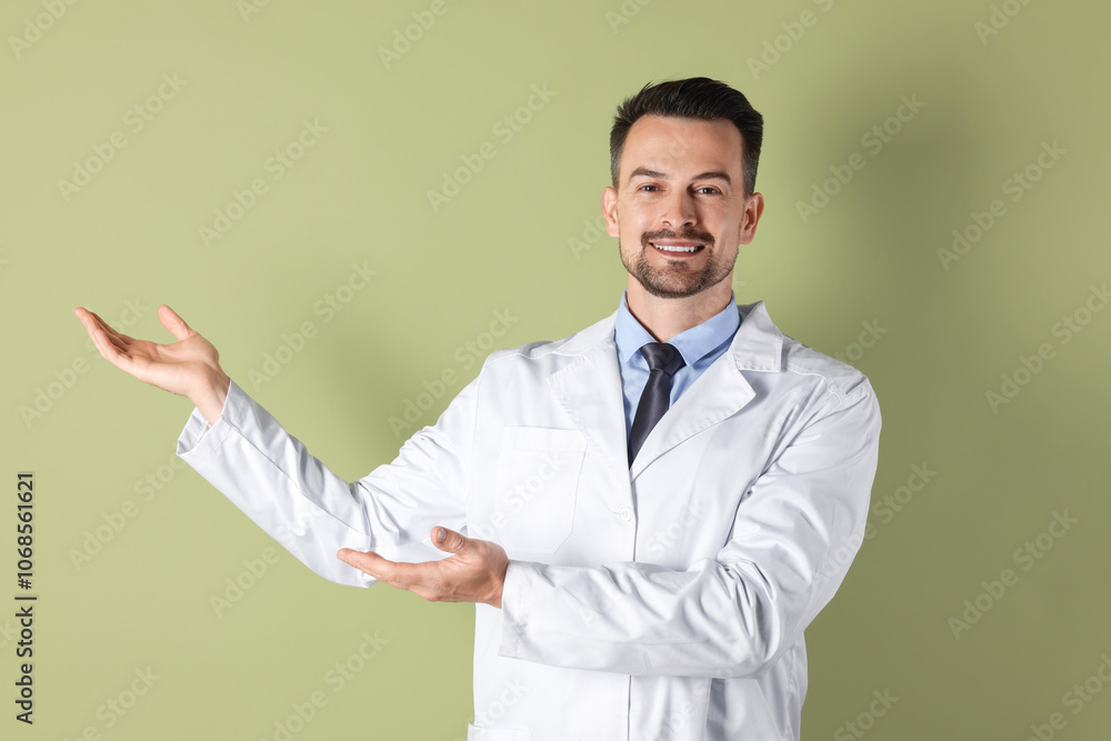 Smiling doctor pointing at something on olive background Smiling doctor pointing at something on olive background