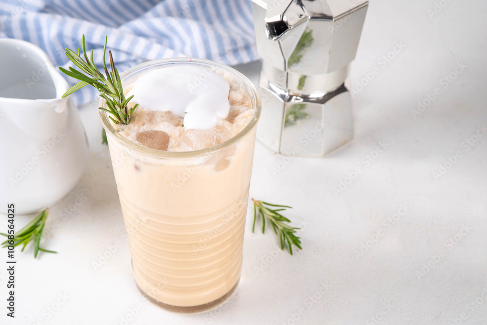 Glass of iced scented aromatic rosemary coffee latte, with whipped milk or cream, cold coffee drink decorated with sprig of rosemary Glass of iced scented aromatic rosemary coffee latte, with whipped milk or cream, cold coffee drink decorated with sprig of rosemary
